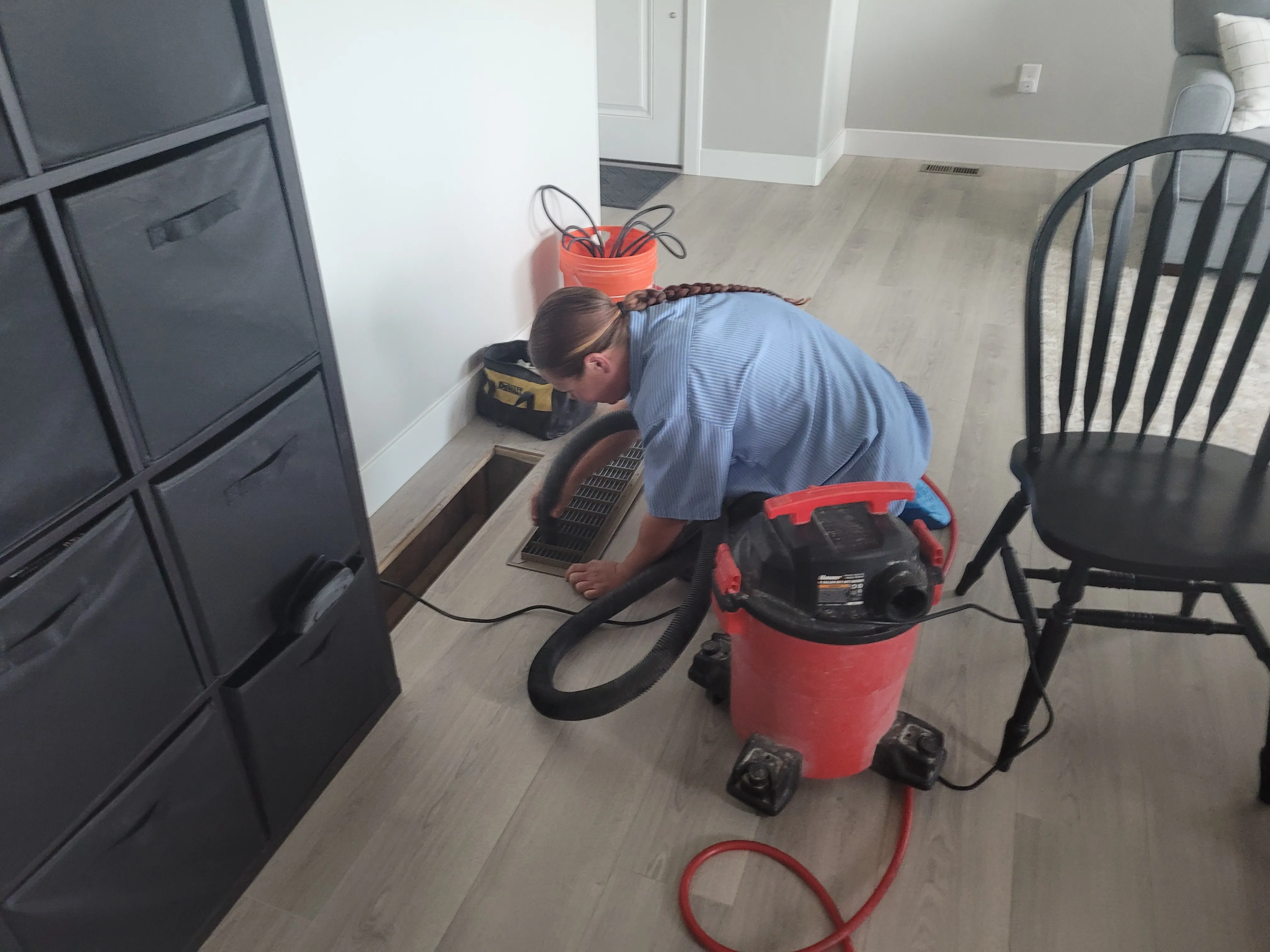 A woman vacuuming a duct cover