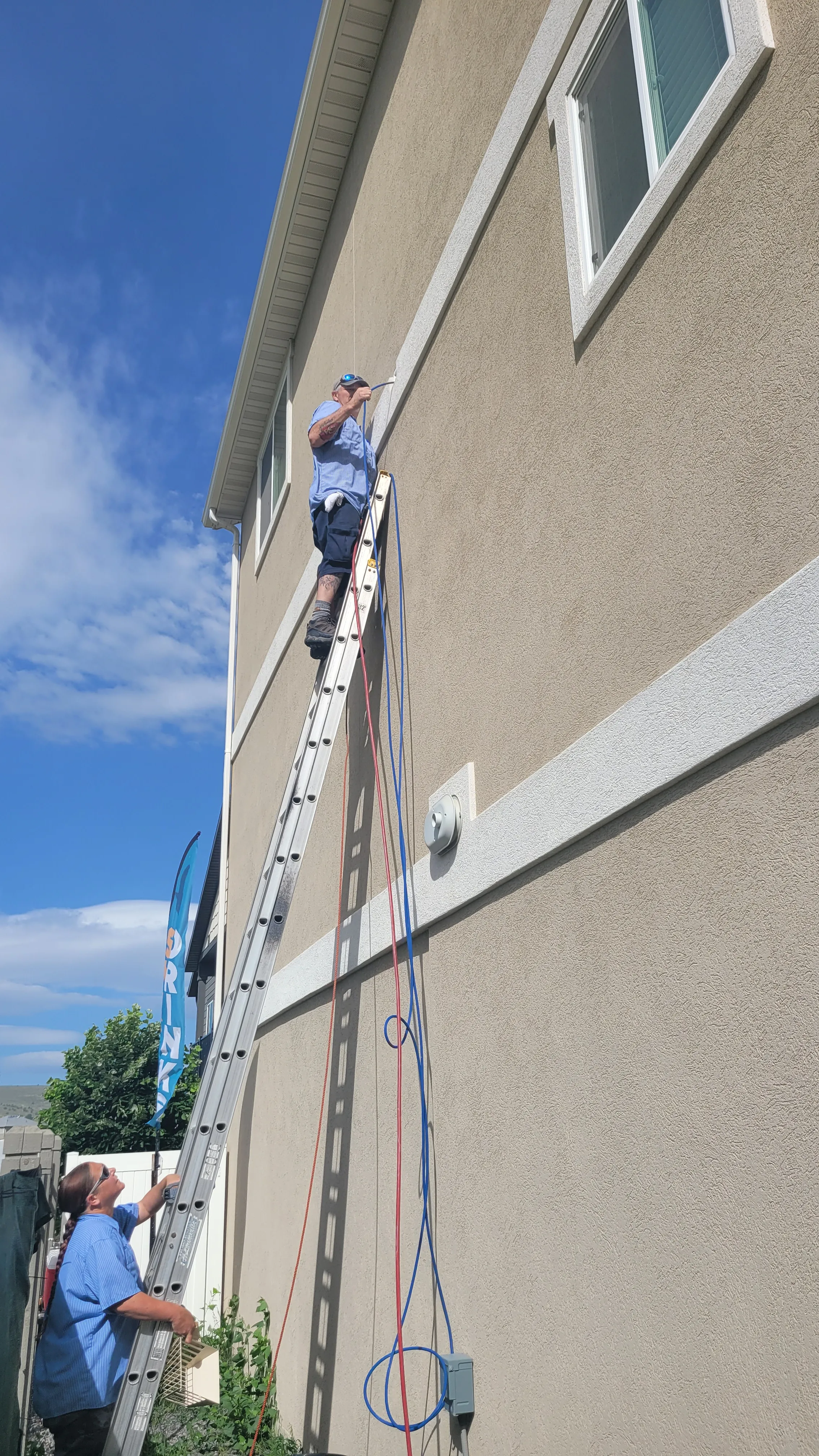 A person on a ladder cleaning a duct